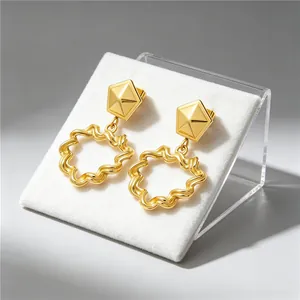 Close-up of gold plated stainless steel earrings with wavy texture and geometric studs