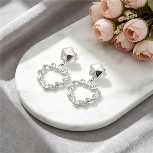 Detail of silver stainless steel earrings with hollow heart and pleated texture.