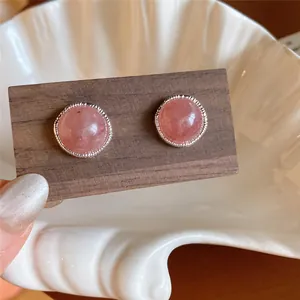 Detalle de pendientes de botón redondos de ágata rosa con borde plateado texturizado