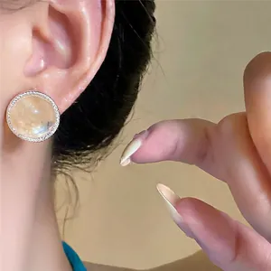 Primer plano de un pendiente redondo de plata con piedra ágata ámbar y pavé de cristales