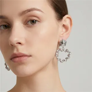 Detail of silver stainless steel heart earrings with wavy pleated texture on model