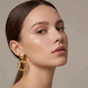 Elegant close-up of golden geometric pleated wavy circle stainless steel drop earrings on a model