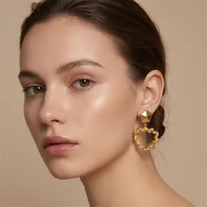 Close-up of vintage gold heart-shaped earrings with wrinkled texture on model