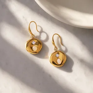 Close-up of gold-plated stainless steel earrings with natural stones on marble background