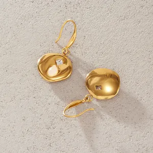 Macro detail of gold stainless steel earrings featuring natural stone and zircon inlay