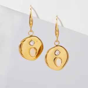 Macro detail of stainless steel gold earrings with natural opal and zircon inlay stones.