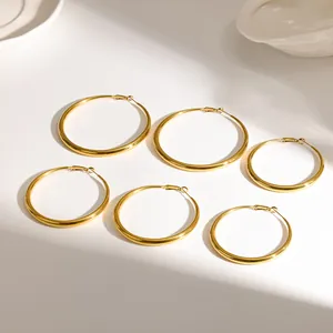 Macro view of several 18K gold-plated stainless steel hoop earrings on white surface