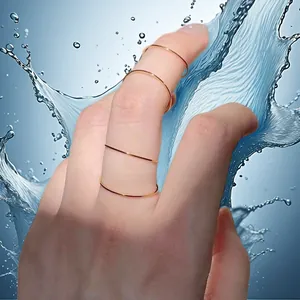 Κοντινό πλάνο λεπτών χρυσών δαχτυλιδιών 0,5 mm από ανοξείδωτο χάλυβα στο δάχτυλο με νερό