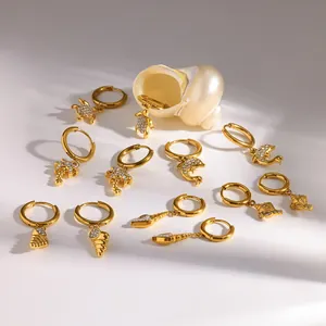 Goldene Edelstahl-Creolen mit maritimen Anhängern und funkelnden Steinen im Detail