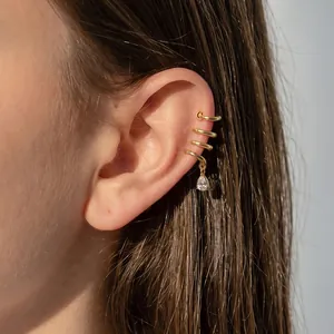 Close-up of golden stainless steel spiral ear cuff with teardrop crystal pendant