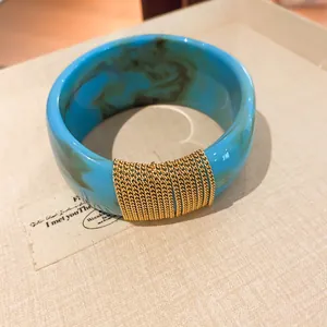 Close-up detail view of turquoise marbled acrylic bangle with wrapped gold chains