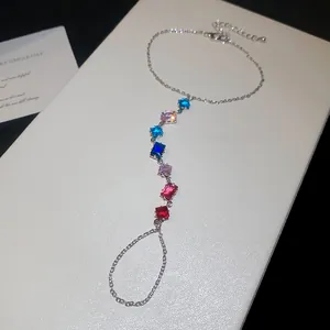 Détail d'une parure de main en argent ornée de zircons multicolores de forme carrée brillante.