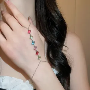 Détail d'un bracelet bague en argent orné de zircons rectangulaires colorés sur la main.