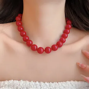 Primer plano de un collar de cuentas de acrílico rojo en el cuello de una modelo detalle.