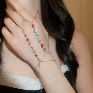 Détail d'une chaîne de main argentée ornée de zircons rectangulaires multicolores.
