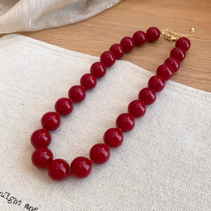 Primer plano de collar étnico con cuentas de acrílico rojo brillante y cierre dorado