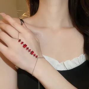 Détail d'un bracelet bague en argent avec zircons rouges scintillants sur la main du modèle