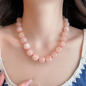 Detalle de collar étnico con cuentas redondas de acrílico y cordón rojo en modelo