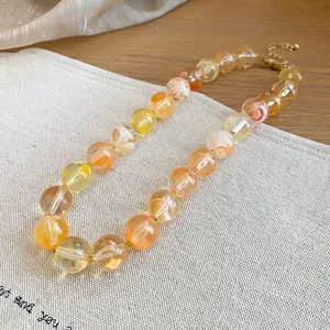 Primer plano de un collar étnico de cuentas acrílicas con patrón de remolino naranja.