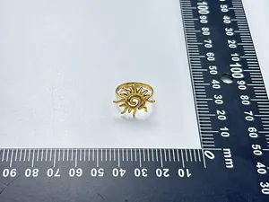 Sonnenring aus goldfarbenem Edelstahl mit Spiralmotiv auf einem Millimetermaßstab gezeigt