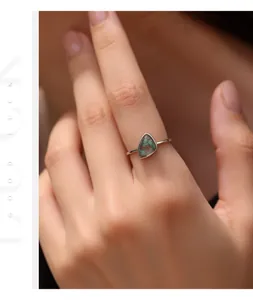 Dettaglio ravvicinato di un anello in agata verde irregolare su un dito femminile
