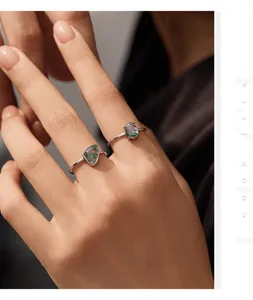Close-up view of 925 sterling silver rings featuring synthetic moss agate stones on hand