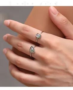 Close-up of two S925 sterling silver rings featuring green moss agate worn on a hand.