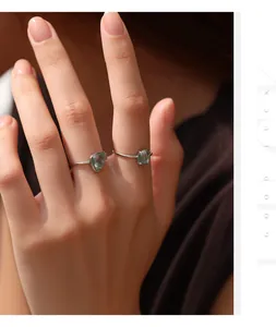 Detailed view of two S925 sterling silver rings with green moss agate on a hand