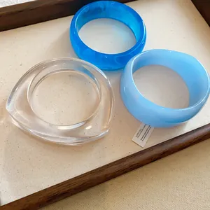 Nahaufnahme von drei stylischen, klobigen Harz-Armreifen in Blau und Transparent.