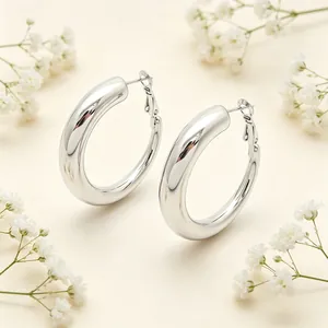 Détail macro de boucles d'oreilles créoles épaisses en acier inoxydable poli argenté