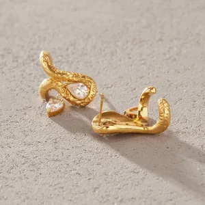 Vista macro detallada de pendientes de serpiente en acero dorado con circones de pera