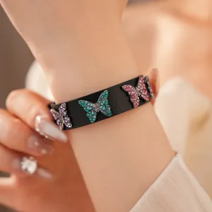 Vue détaillée d'un bracelet en cuir noir avec des breloques papillon en strass colorés