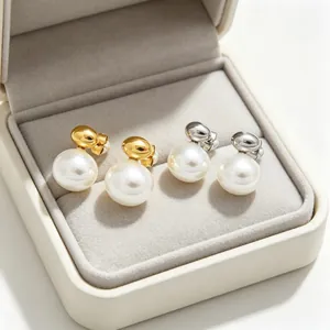 Close-up of gold and silver minimalist pearl stud earrings displayed in a luxury box