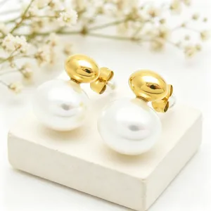 Close-up of elegant gold oval studs with white shell pearls on a white stand