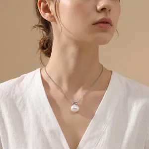 Detail view of an elegant white oval shell pendant on a silver stainless steel link chain.