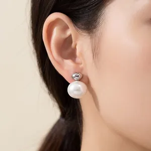 Close-up detail of a minimalist white pearl earring worn on a female ear in natural light