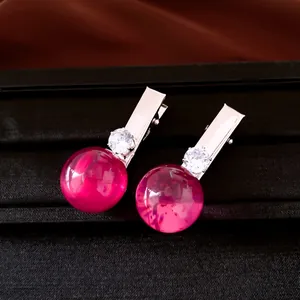 Detailansicht von magenta-farbenen Haarspangen aus Harz mit funkelnden Kristallen.