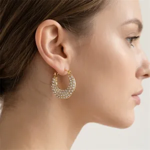 Vue détaillée de boucles d'oreilles créoles dorées en acier inoxydable avec strass