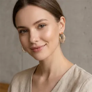 Gros plan de boucles d'oreilles créoles ovales dorées pavées de cristaux sur un modèle