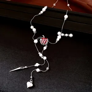Élégant collier de perles avec pendentif pomme rouge et breloque cœur sur fond sombre