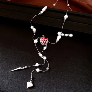 Détail du pendentif pomme rouge et des glands de perles de ce collier de luxe