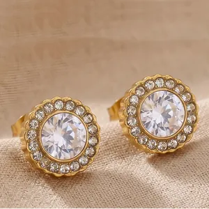 Détail de boucles d'oreilles rondes en acier doré avec des pierres de zircone blanche.