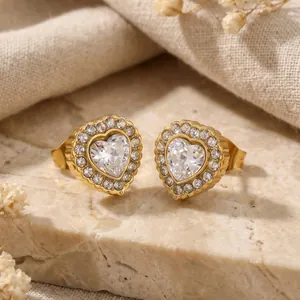 Détail macro de boucles d'oreilles cœur en acier inoxydable doré avec zircons blancs