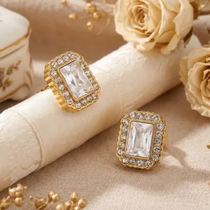Détail de boucles d'oreilles en acier doré avec zircons blancs taille émeraude et halo
