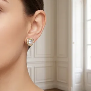 Détail d'une boucle d'oreille cœur dorée avec zircon étincelant portée par un mannequin