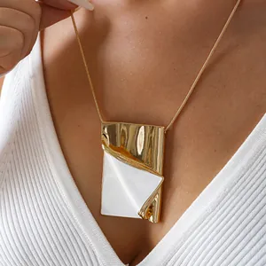 Detailed macro view of a creative gold book pendant necklace with white enamel inlay