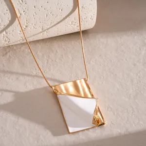 Detailed view of creative gold book pendant necklace with white enamel inlay