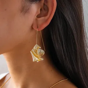 Close-up of elegant gold crumpled metal earring on model, showcasing unique artistic texture.