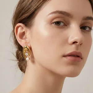 Gros plan de boucles d'oreilles œil porte-bonheur en acier doré avec perle sur mannequin