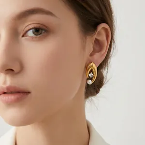 Gros plan d'une boucle d'oreille en acier doré en V avec perle et diamant portée.